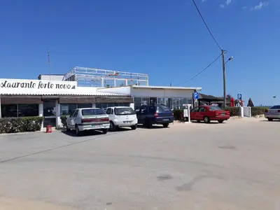 a parking lot with cars parked in front of a building at T1 V do Forte AC&Piscina&Garagem in Quarteira