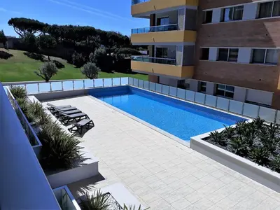 a swimming pool in front of a building at T1 V do Forte AC&Piscina&Garagem in Quarteira