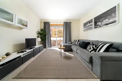 a living room with a gray couch and a tv at T1 V do Forte AC&Piscina&Garagem in Quarteira