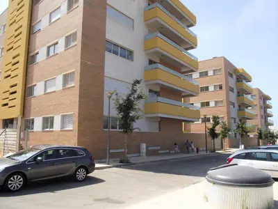 two cars parked in a parking lot in front of a building at T1 V do Forte AC&Piscina&Garagem in Quarteira
