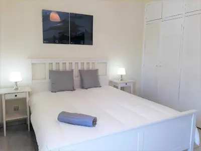 a large white bed with a blue pillow on it at Mouramar- Garagem, Piscina & Wifi in Vilamoura