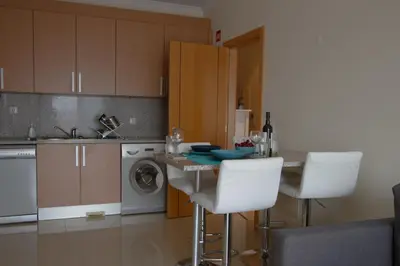 a kitchen with a table and two white bar chairs at Monte da Eira in Albufeira