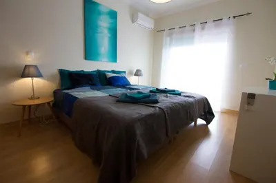 a bedroom with a bed with blue sheets and a window at Monte da Eira in Albufeira