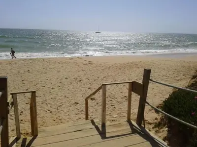 a person walking on the beach near the ocean at Apartamento Praia da Falésia in Albufeira