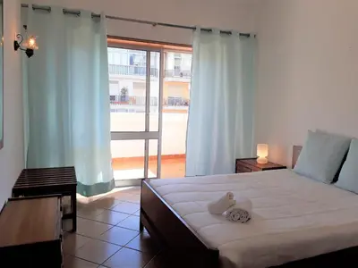 a bedroom with a large bed and a large window at T2 Mira Praia 4- Familiar, 80mt Praia, Wifi in Quarteira