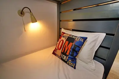 a bedroom with a bed with a pillow and a lamp at Son of a Beach Hostel in Albufeira