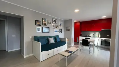 a living room with a couch and a kitchen with red at Apartamento Villa Bellevue vista mar in Albufeira