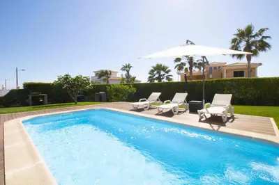 a swimming pool with two chairs and an umbrella at Apartamento Villa Bellevue vista mar in Albufeira