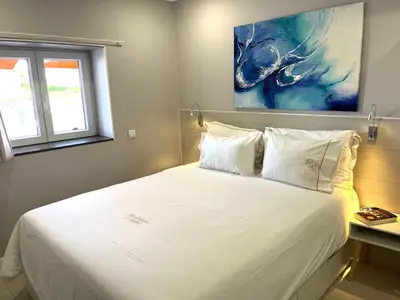 a bedroom with a white bed with a painting on the wall at Apartamento Villa Bellevue vista mar in Albufeira