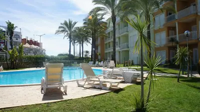 a pool with chairs and palm trees next to a building at Pool & Garden Oura Albufeira Flat in Albufeira