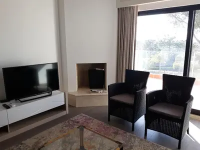 a living room with two chairs and a flat screen tv at Victory Village Club in Quinta do Lago