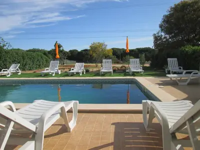 a group of white chairs sitting around a pool at Quinta Das Palmeiras in Quarteira