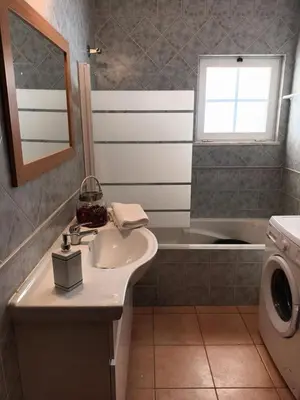 a bathroom with a sink and a washing machine at Quinta Das Palmeiras in Quarteira