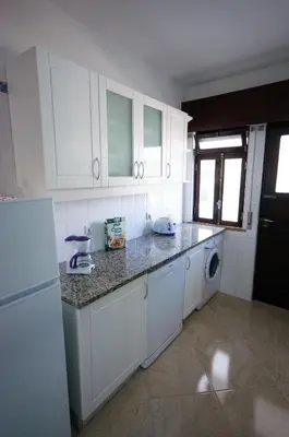a kitchen with white cabinets and a washer and dryer at Old Town Sant'ana T2 in Albufeira