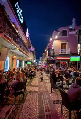 a crowd of people sitting in chairs on a street at night at Estrela do Mar in Albufeira