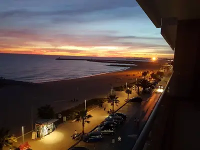 a view of a beach at sunset with cars parked at ocean blue in Quarteira
