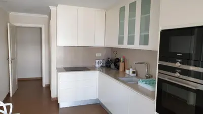 a kitchen with white cabinets and a black microwave at ocean blue in Quarteira