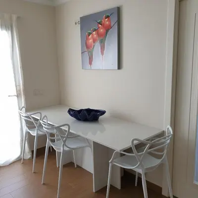 a white table with chairs and a painting on the wall at ocean blue in Quarteira