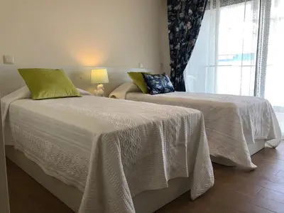 a bedroom with two beds with white sheets and a window at ocean blue in Quarteira