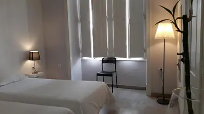 a bedroom with a bed and a chair and a lamp at Hostel A Casa da Árvore in Faro