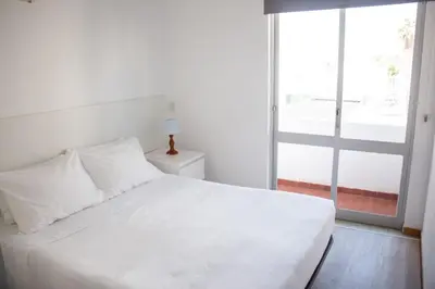 a bedroom with a white bed and a large window at Apartamentos Central in Quarteira