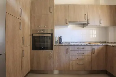 a kitchen with wooden cabinets and an oven at Apart JCMar - Near to the beach - WIFI - BY BEDZY in Albufeira