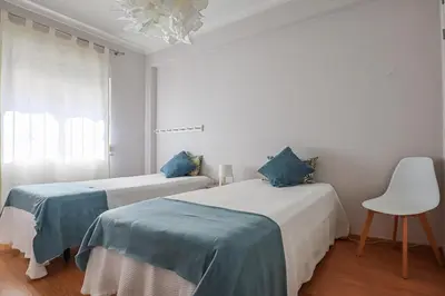 a bedroom with two beds and a chair and a chandelier at Apart JCMar - Near to the beach - WIFI - BY BEDZY in Albufeira