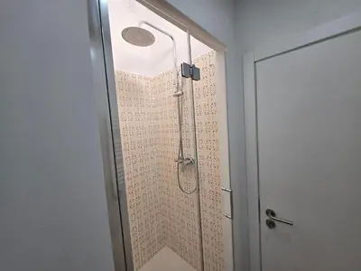 a shower with a glass door in a bathroom at Casa da avó Bia in Faro
