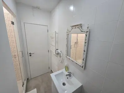 a white bathroom with a sink and a mirror at Casa da avó Bia in Faro