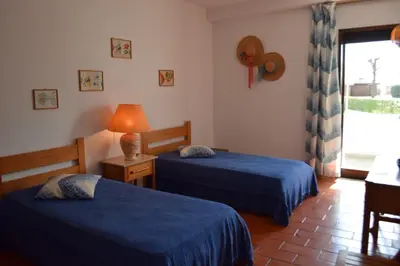 a hotel room with two beds and a window at Apartamento T2 com Piscina e Wifi a 350 metros da Praia in Roja- Pé