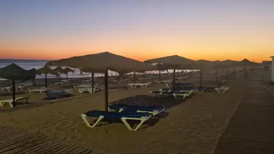 a group of chairs and umbrellas on a beach at Marina Apartment in Quarteira