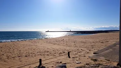 a sandy beach with a pier in the ocean at Marina Apartment in Quarteira