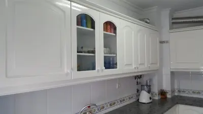 a white kitchen with a sink and white cabinets at Austral Apartment in Quarteira