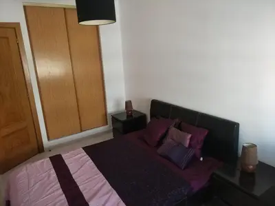 a bedroom with a bed with purple sheets and pillows at Austral Apartment in Quarteira