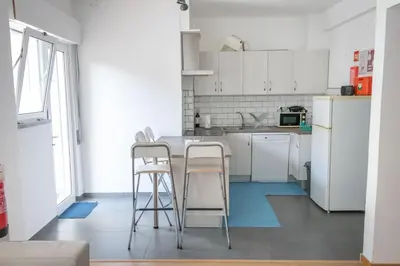 a kitchen with white cabinets and a table and stools at Casa Gago in Faro