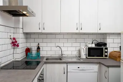 a kitchen with white cabinets and a sink and a microwave at Casa Gago in Faro