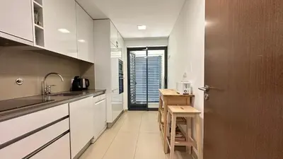 a kitchen with white cabinets and a sink and a door at Cavalo Prеto Holiday apartment 200m to the beach in Quarteira