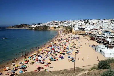 a crowd of people on a beach with umbrellas at Edifício Albufeira 406 in Albufeira