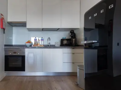 a kitchen with white cabinets and black appliances at Apartamento Deluxe AM in Quarteira