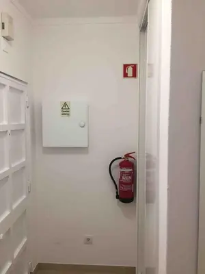 a white hallway with a fire extinguisher on the wall at sol nascente in Vilamoura