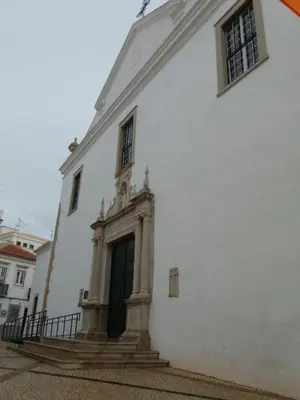 a white building with a black door and stairs at Guest House Capitao Mor in Faro