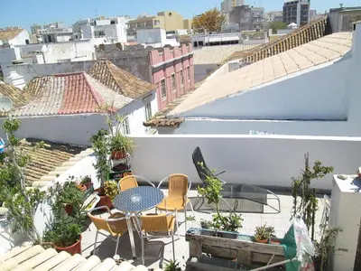 a patio with a table and chairs on a roof at Guest House Capitao Mor in Faro