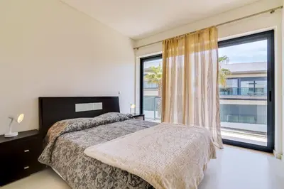 a bedroom with a bed and a large window at Cavalo Preto Beach Resort in Quarteira