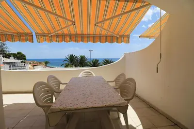 a table and chairs on a balcony with a view of the ocean at venha nadar a oura in Albufeira