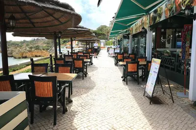 an outdoor restaurant with tables and chairs and umbrellas at venha nadar a oura in Albufeira