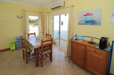 a dining room with a table and chairs and a window at venha nadar a oura in Albufeira