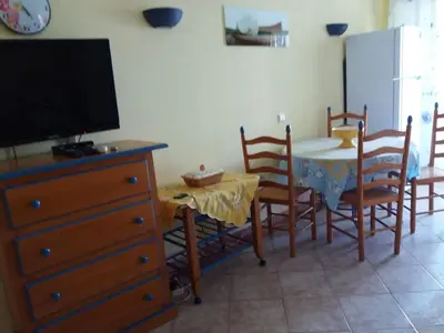 a dining room with a table with chairs and a television at venha nadar a oura in Albufeira