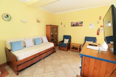 a bedroom with a bed and two chairs and a desk at venha nadar a oura in Albufeira