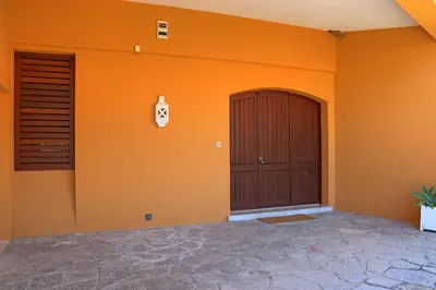 a house with an orange wall with a door at Casa da Palmeira, pool & soccer pitch in Vilamoura