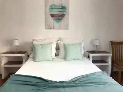 a bed with green and white sheets and pillows at BREEZY NEST by ITHOUSE in Albufeira